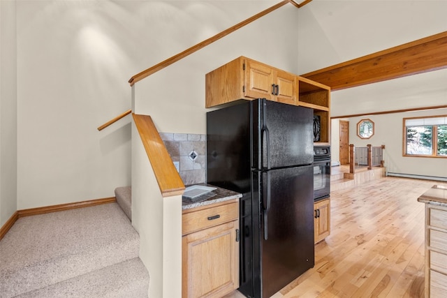 kitchen with light brown cabinets, black appliances, a baseboard radiator, and light hardwood / wood-style floors