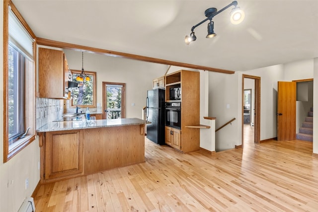 kitchen featuring kitchen peninsula, decorative backsplash, a baseboard heating unit, black appliances, and light hardwood / wood-style flooring