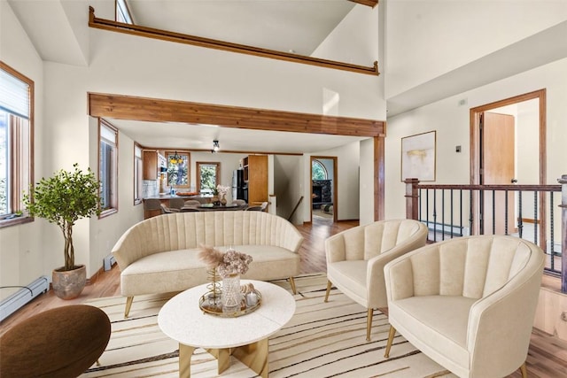 interior space featuring beamed ceiling, light hardwood / wood-style floors, baseboard heating, and ceiling fan