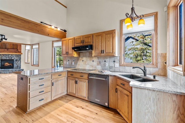 kitchen with pendant lighting, dishwasher, a stone fireplace, sink, and kitchen peninsula