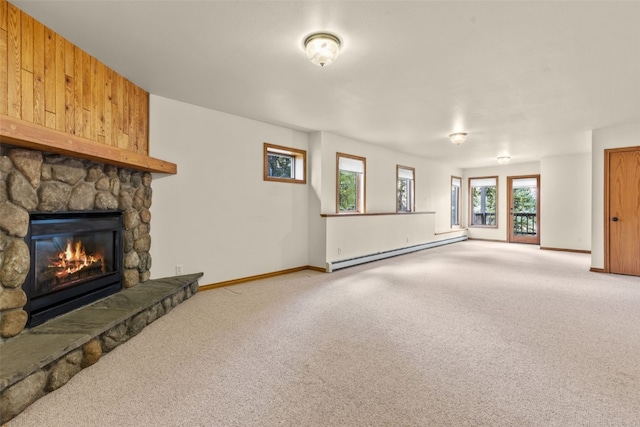 unfurnished living room with carpet, a baseboard radiator, and a stone fireplace