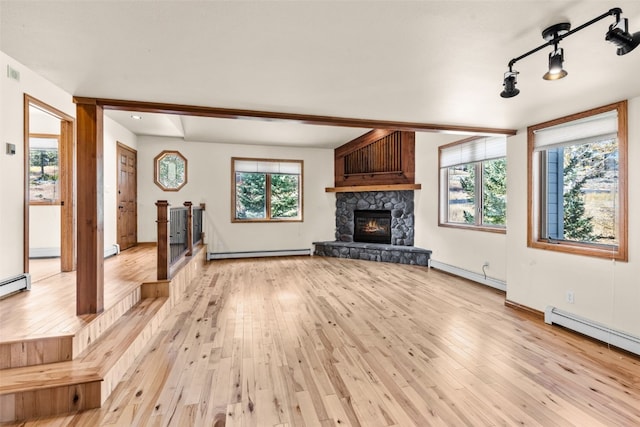 unfurnished living room featuring plenty of natural light, light hardwood / wood-style floors, a fireplace, and a baseboard radiator