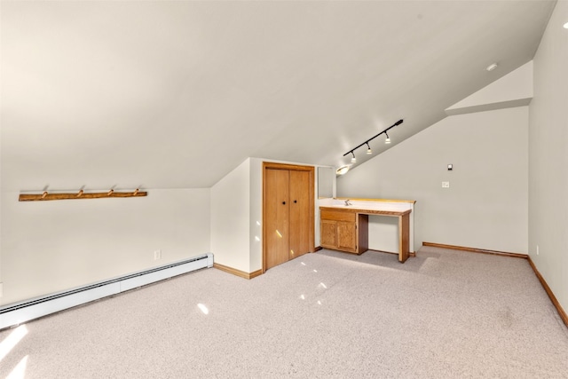 additional living space featuring lofted ceiling, light carpet, and a baseboard heating unit