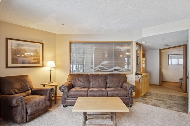 living area with light colored carpet, baseboards, and a textured ceiling