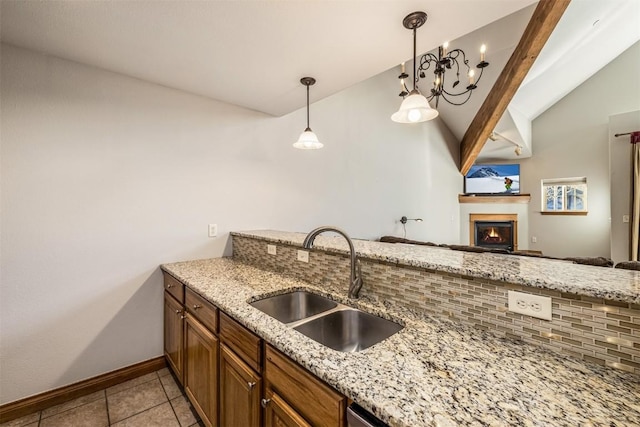 kitchen with pendant lighting, lofted ceiling with beams, sink, light tile patterned floors, and light stone counters