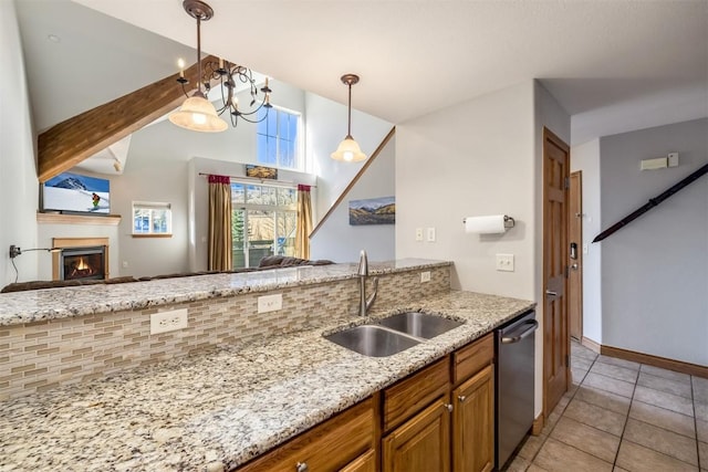 kitchen featuring dishwasher, sink, light tile patterned floors, decorative light fixtures, and light stone counters