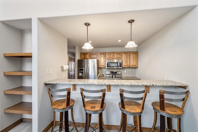 kitchen with kitchen peninsula, tasteful backsplash, light stone counters, stainless steel appliances, and hanging light fixtures