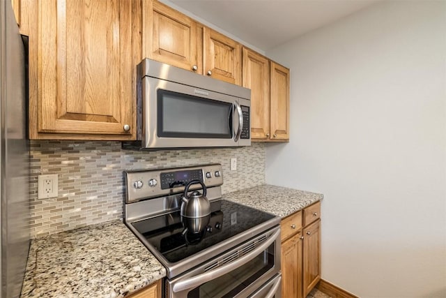 kitchen featuring tasteful backsplash, light stone counters, and appliances with stainless steel finishes