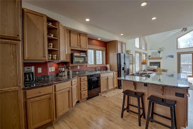 kitchen featuring dark stone countertops, light hardwood / wood-style flooring, stainless steel appliances, and vaulted ceiling