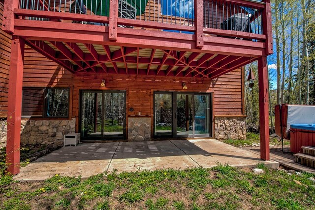 back of property featuring a patio, a deck, and a hot tub