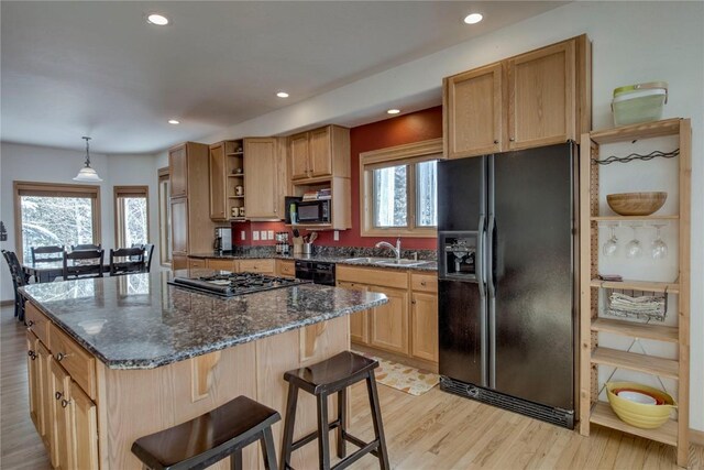 kitchen featuring sink, light wood-type flooring, a center island, and black appliances