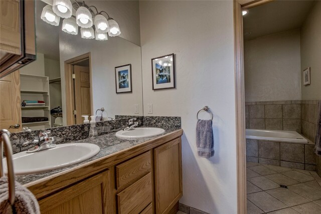 bathroom featuring vanity, a relaxing tiled tub, and tile patterned floors