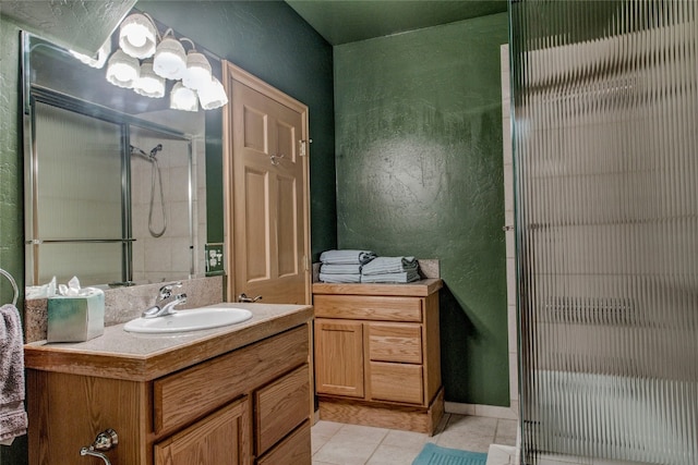 bathroom featuring vanity, an inviting chandelier, tile patterned floors, and a shower with shower door