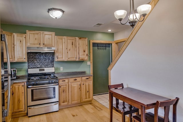 kitchen with light brown cabinetry, gas stove, pendant lighting, a chandelier, and light hardwood / wood-style floors