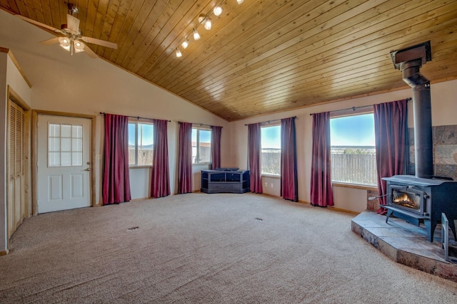 unfurnished room featuring carpet flooring, a wood stove, ceiling fan, high vaulted ceiling, and wood ceiling