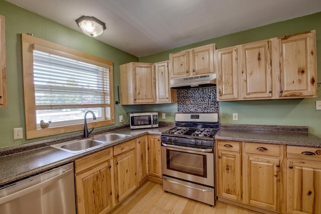 kitchen with appliances with stainless steel finishes, light brown cabinets, light hardwood / wood-style flooring, and sink