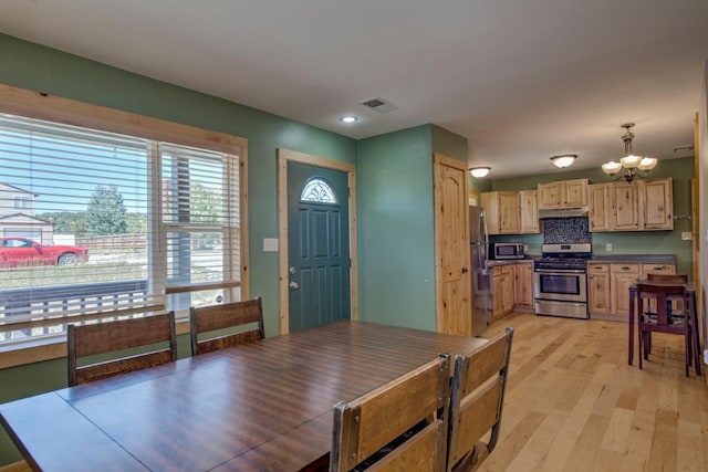 dining space with light hardwood / wood-style floors and a notable chandelier