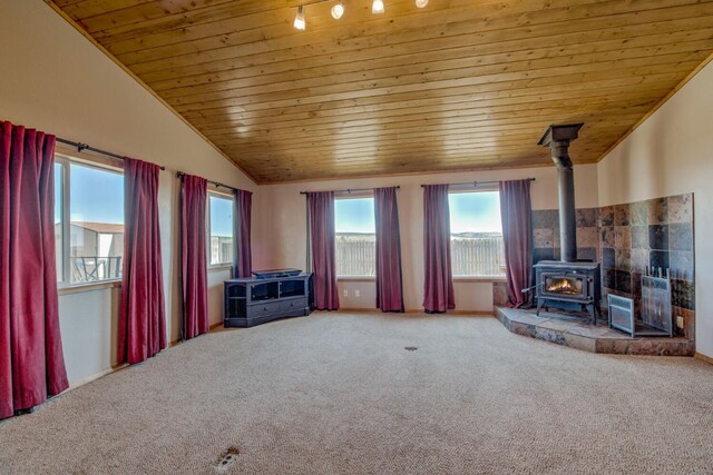 unfurnished living room featuring carpet flooring, a wood stove, wood ceiling, and vaulted ceiling