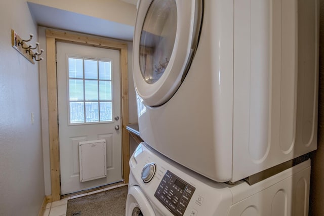 laundry area with light tile patterned floors and stacked washer and clothes dryer