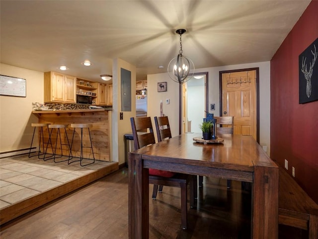 dining space with light wood-type flooring, a baseboard radiator, and a chandelier