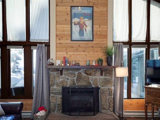 living room with a baseboard radiator, plenty of natural light, wood walls, and a fireplace