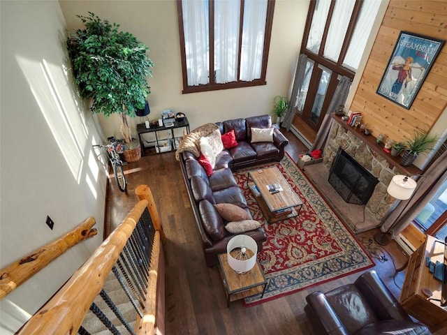 living room featuring a towering ceiling, a fireplace, and dark wood-type flooring