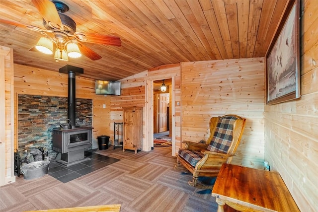 living room with lofted ceiling, a wood stove, wooden walls, and wooden ceiling