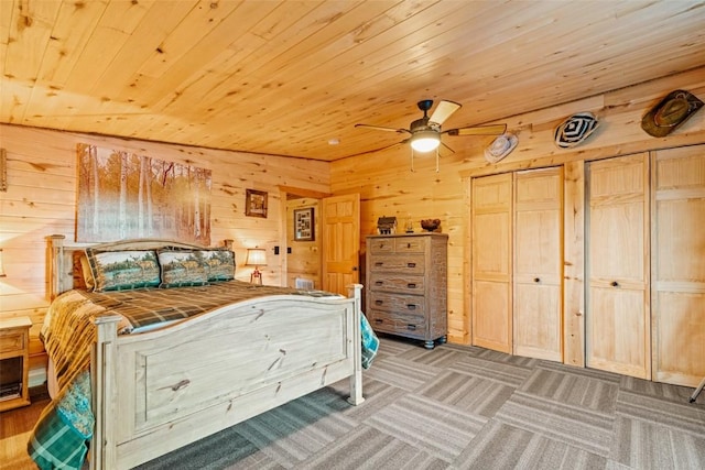 bedroom with wooden walls, ceiling fan, wood ceiling, and two closets