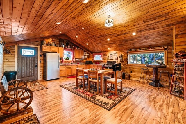 dining space with light hardwood / wood-style floors, lofted ceiling, wood walls, and wood ceiling