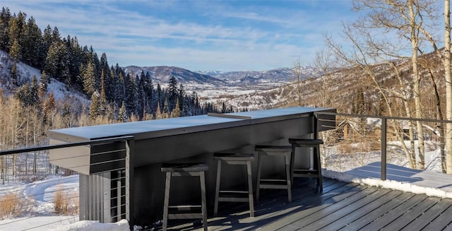 snow covered deck with a bar and a mountain view