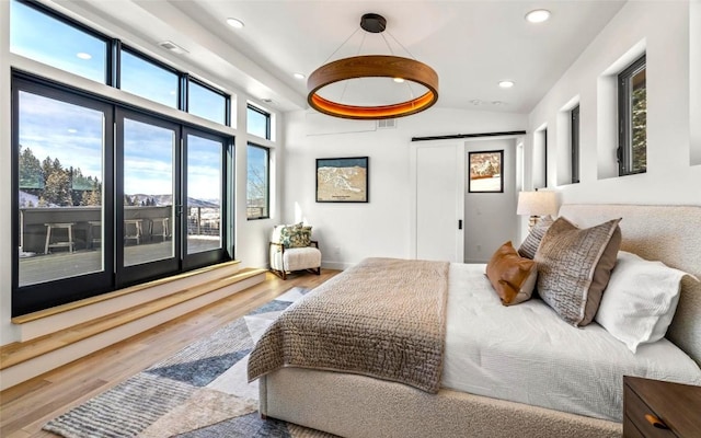 bedroom with lofted ceiling, a barn door, and hardwood / wood-style flooring