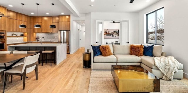 living room featuring ceiling fan, sink, and light hardwood / wood-style floors