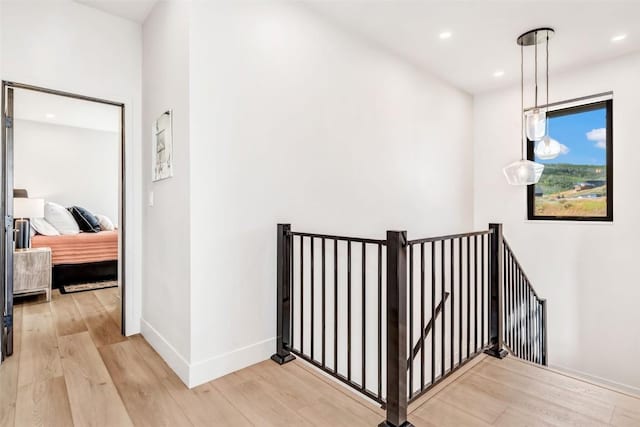 hall featuring light wood-style flooring, recessed lighting, an upstairs landing, and baseboards