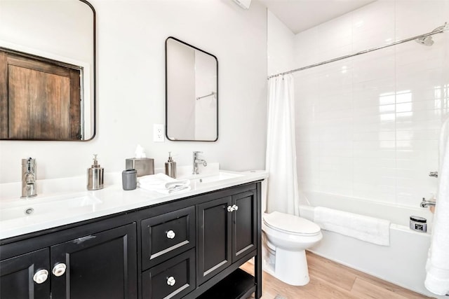 full bath featuring shower / tub combo with curtain, a sink, toilet, and wood finished floors