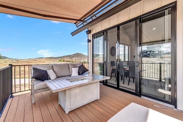 wooden deck with an outdoor living space with a fire pit and a mountain view