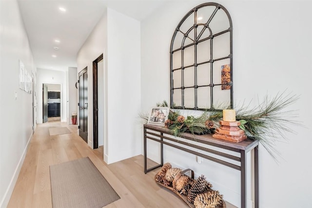 corridor featuring baseboards, light wood-style flooring, and recessed lighting