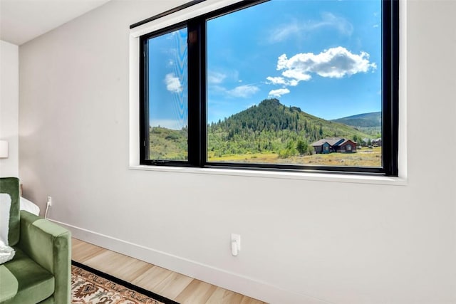 living area with a mountain view, baseboards, and wood finished floors