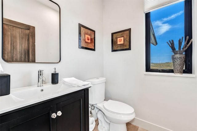 bathroom featuring baseboards, vanity, and toilet