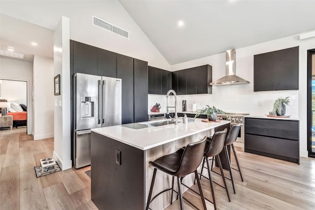 kitchen with premium appliances, a kitchen bar, light countertops, visible vents, and wall chimney exhaust hood