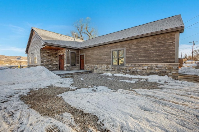 view of front of house featuring stone siding and a shingled roof