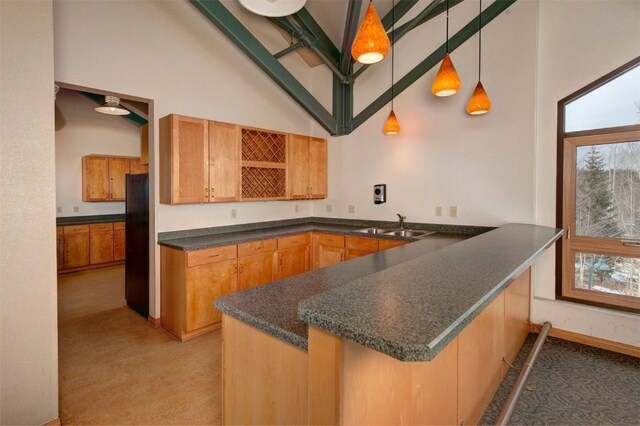 kitchen featuring pendant lighting, high vaulted ceiling, black fridge, sink, and kitchen peninsula