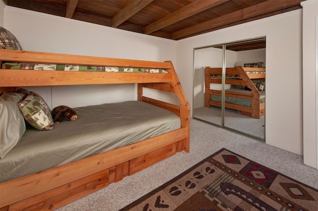 bedroom featuring carpet, a closet, beamed ceiling, and wood ceiling