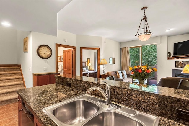 kitchen featuring dark stone counters, sink, light tile patterned floors, dishwasher, and hanging light fixtures