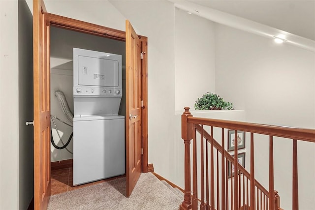 laundry room featuring light colored carpet and stacked washer and clothes dryer