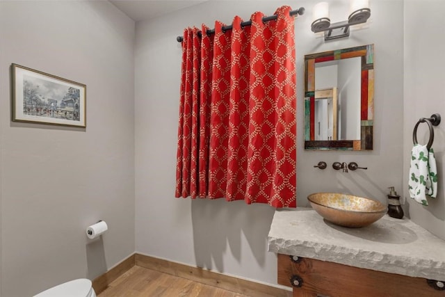 bathroom with vanity, toilet, and wood-type flooring