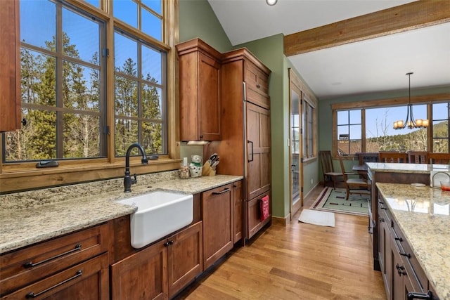 kitchen featuring light stone countertops, sink, light hardwood / wood-style floors, and a notable chandelier