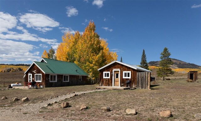 back of property with a mountain view and an outbuilding