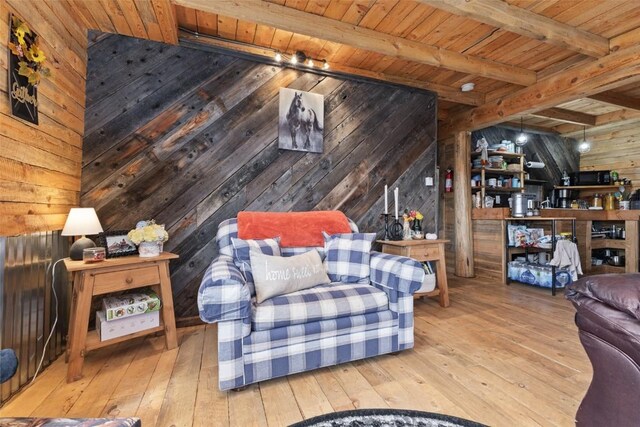 living room with beamed ceiling, wood walls, track lighting, wood ceiling, and light wood-type flooring