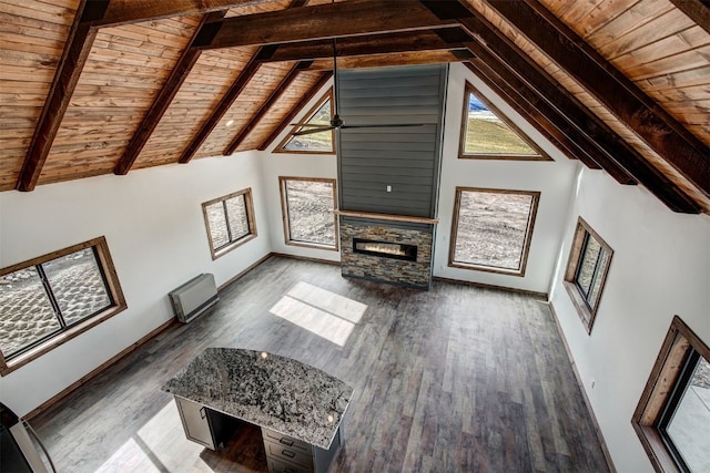 unfurnished living room with hardwood / wood-style floors, wooden ceiling, high vaulted ceiling, a stone fireplace, and beamed ceiling