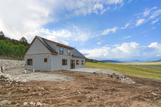 rear view of property with a mountain view, a patio, and a rural view